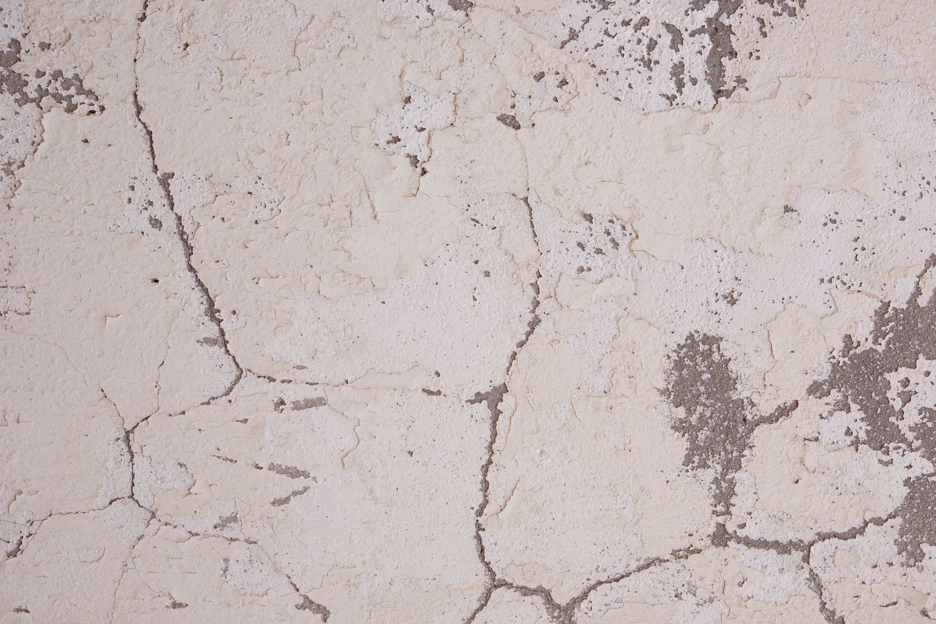High-resolution image of a cracked plaster wall texture with rough surface details, ideal for backgrounds and design.