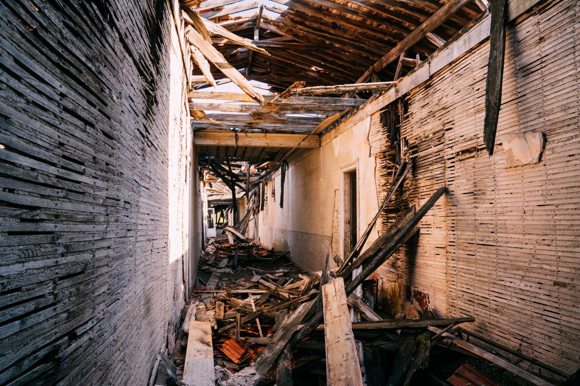 Explore the haunting interior of an abandoned building with a collapsed roof and debris-filled hallway.