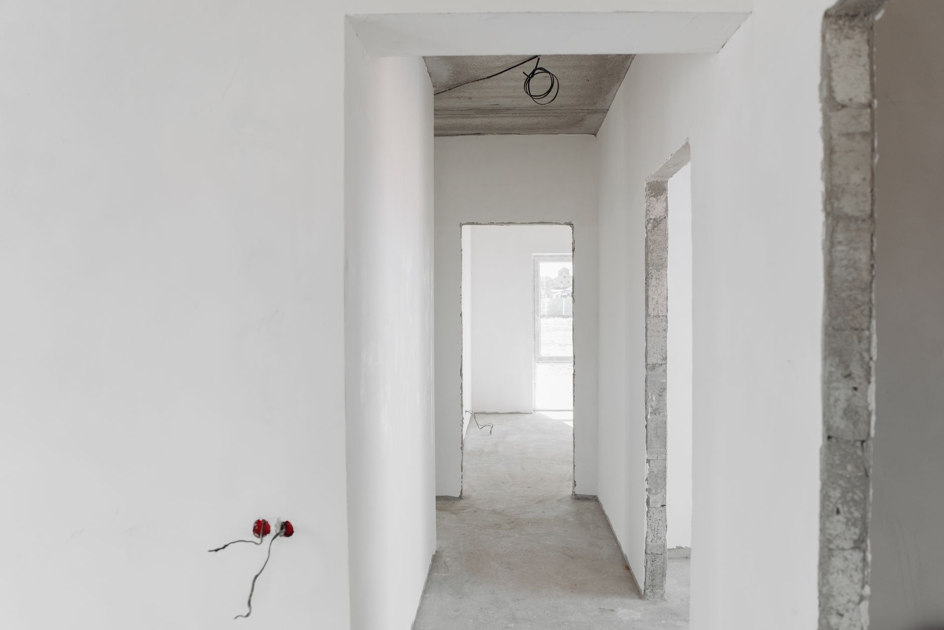 A minimalist view of an unfinished building interior with white walls and door frames.