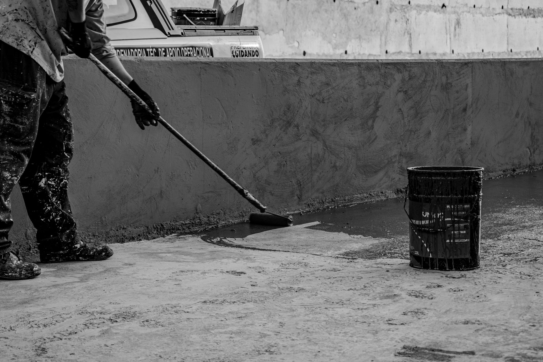 Black and white photo of a construction worker painting a wall outdoors in Londrina, Brazil.