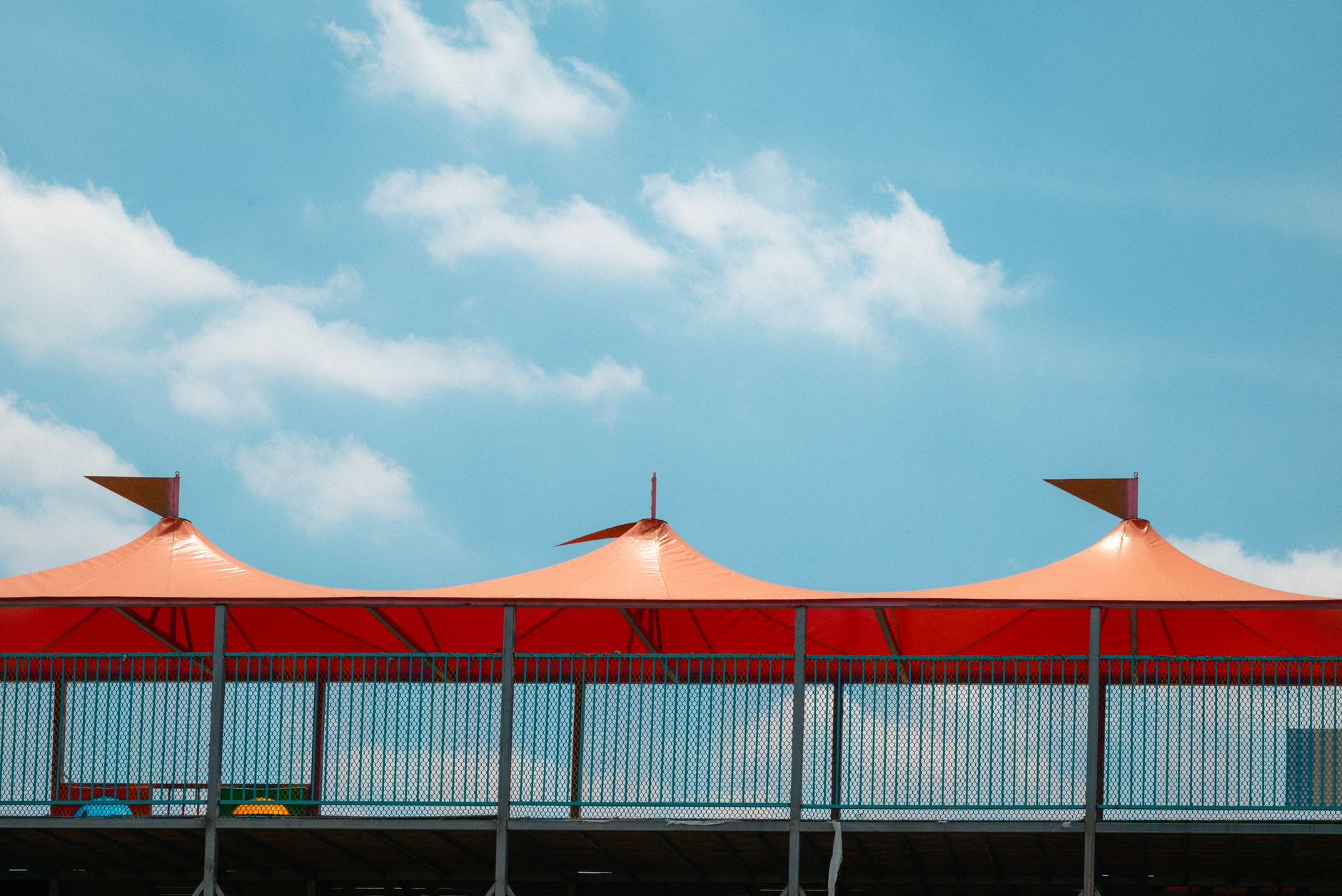 Vivid red canopy structure with a clear blue sky backdrop, modern and architectural.