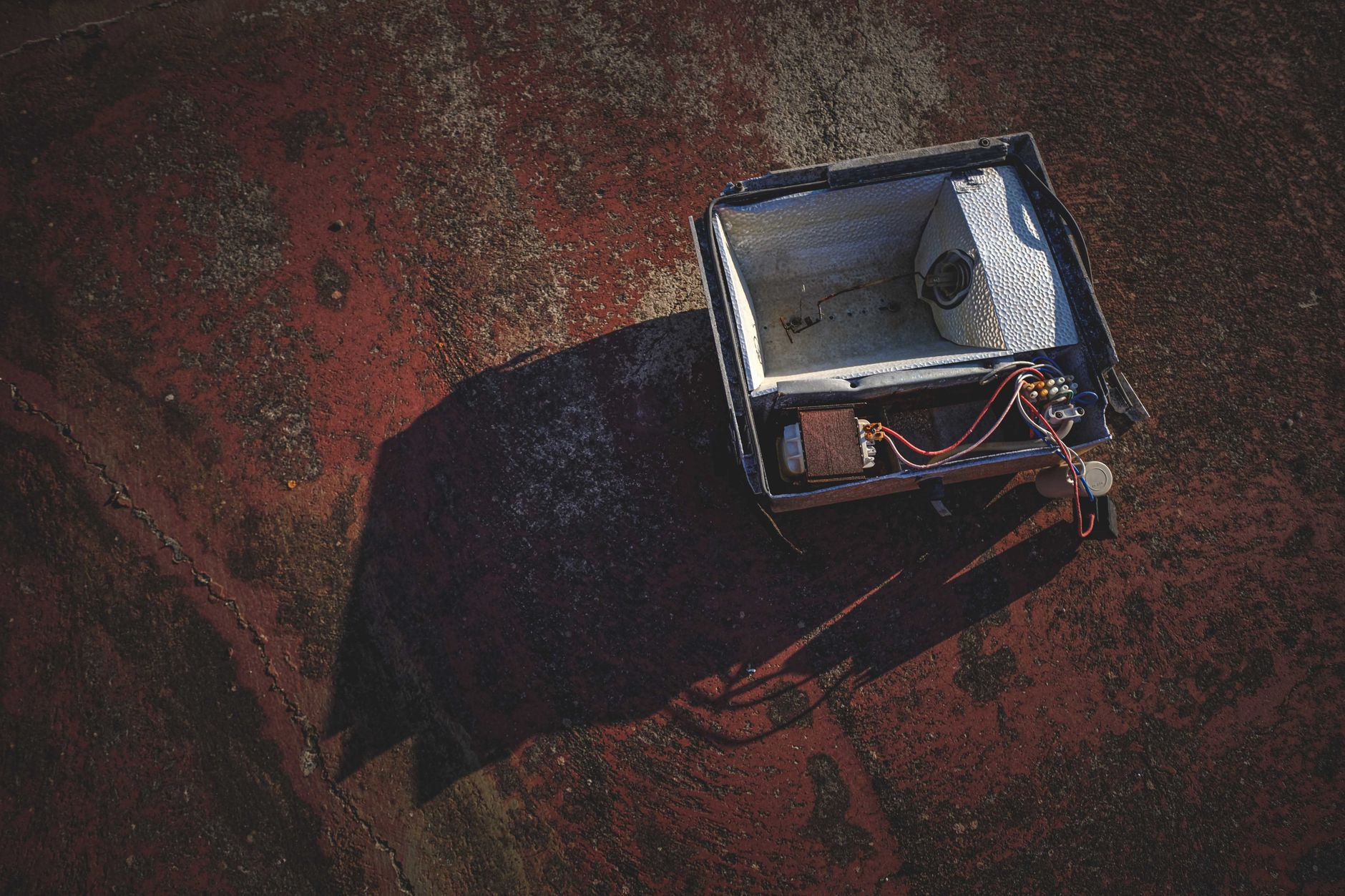 Top view of a damaged floodlight on a weathered, rusty concrete surface.