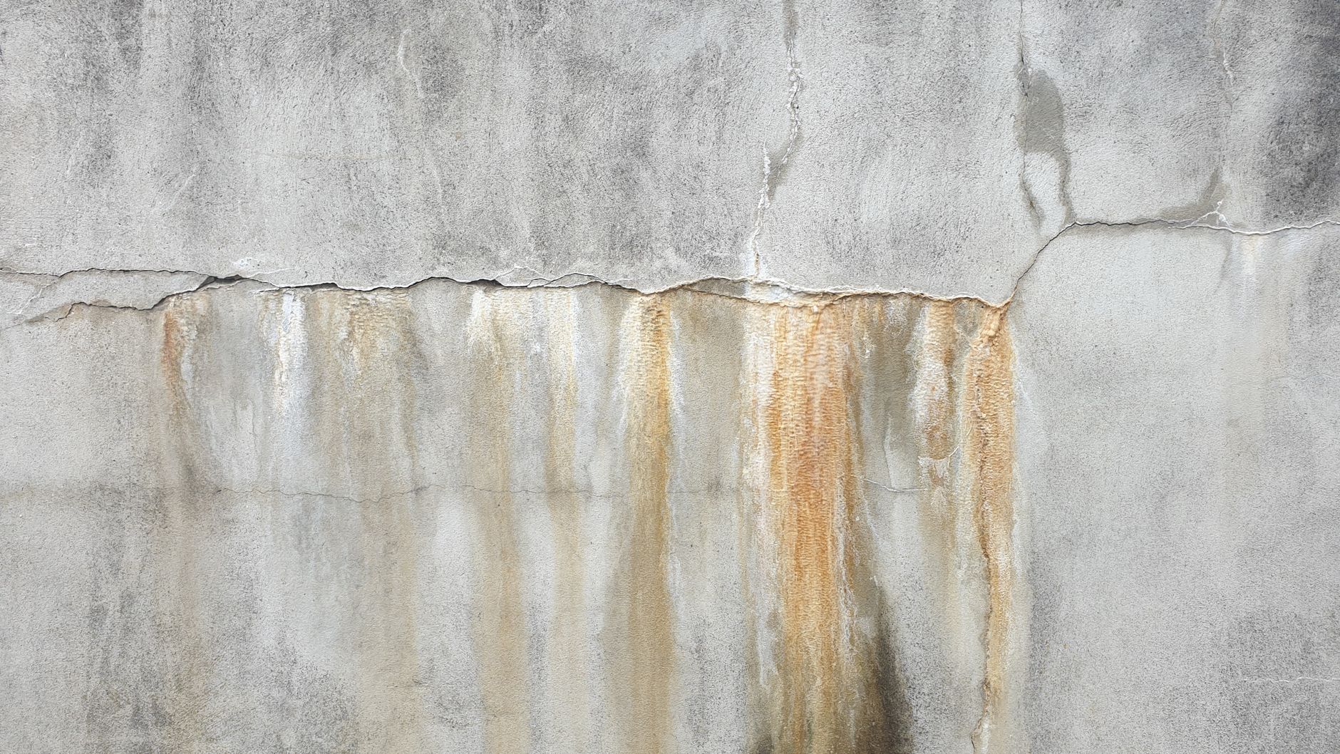 Textured concrete wall with visible cracks and stains, perfect for backgrounds.