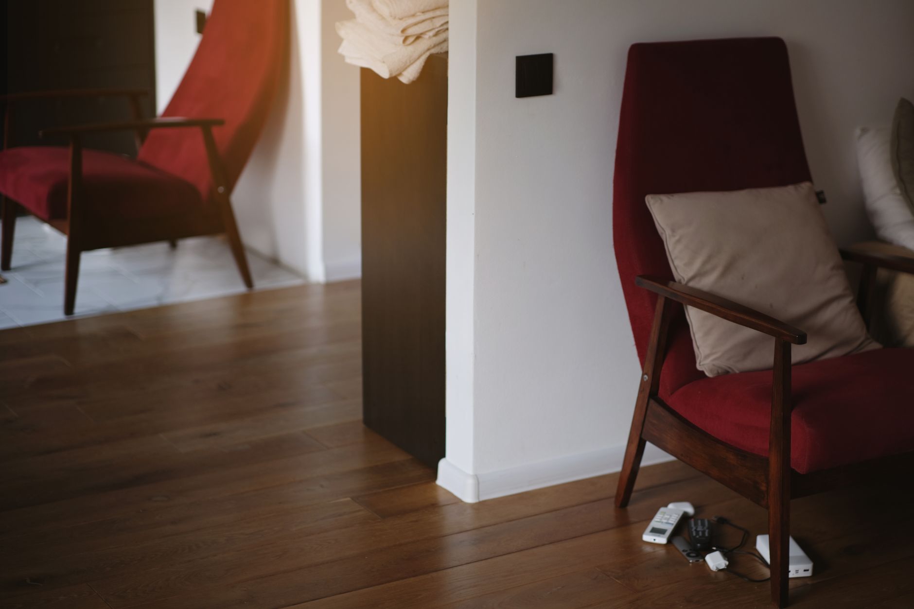 Stylish red armchair with wooden legs in a warm, minimalist living room setting.