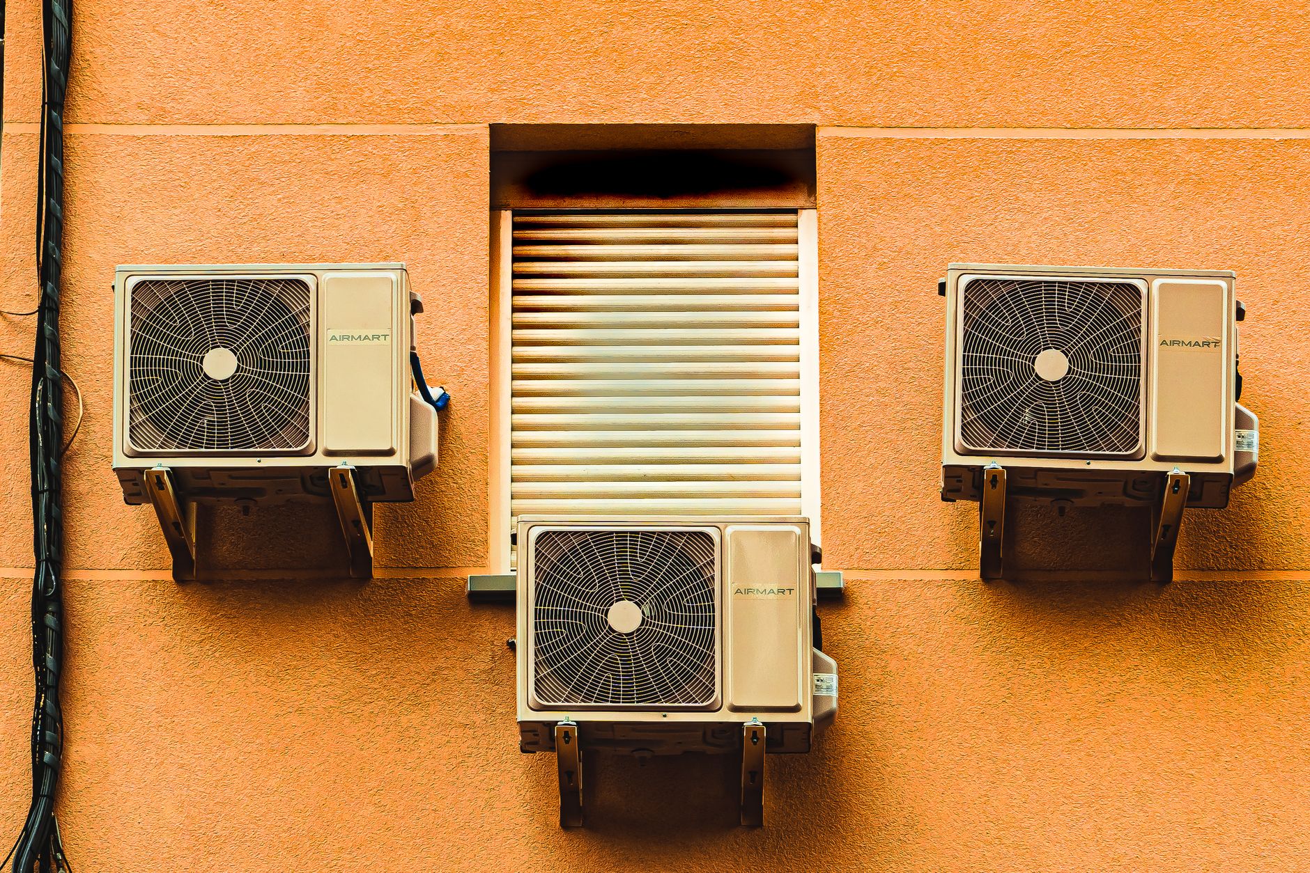 Exterior wall with three air conditioners, showcasing modern architectural elements.